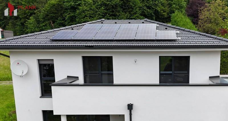 Modernes Haus mit Photovoltaikanlage auf dem Dach und weißer Fassade.