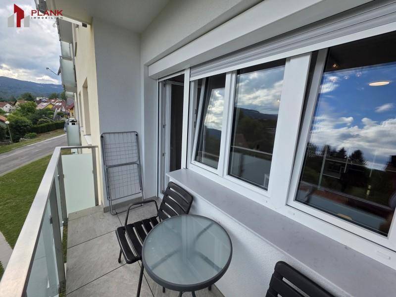 Balkon mit Sitzgelegenheiten und Ausblick auf die umliegende Landschaft und Berge.
