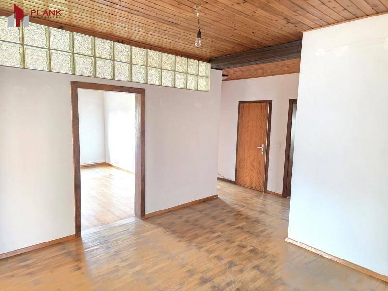 Flur mit Holzdeckenverkleidung und dekorativen Glasbausteinen, der zu weiteren Räumen führt.