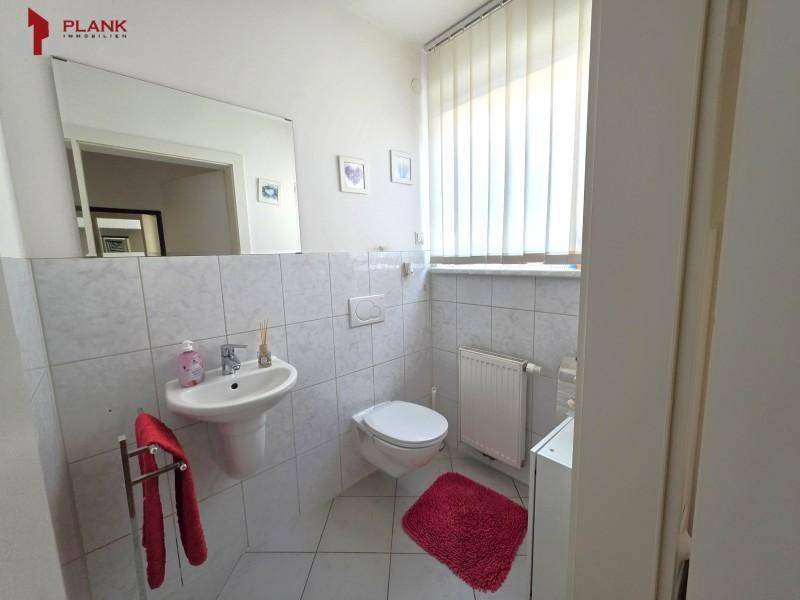Helles Gäste-WC mit weißen Fliesen, Waschbecken und Fenster für natürliche Belüftung.