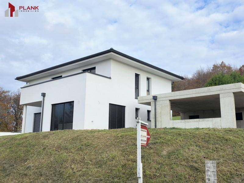 Modernes Einfamilienhaus mit weißer Fassade und im Bau befindlichem Carport.