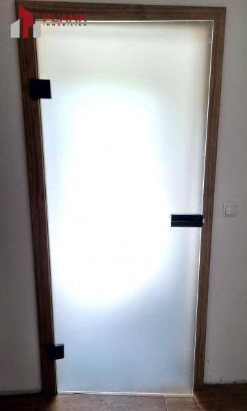 Moderne Milchglastür mit Holzzargen und schwarzen Beschlägen.