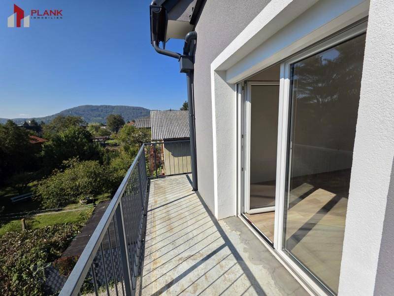 Geräumiger Balkon mit Metallgeländer und Schiebetür, der einen Blick auf grüne Hügel bietet.