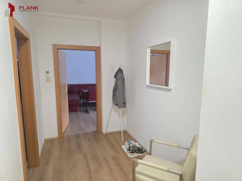 Heller Flur mit Garderobe, Spiegel und Zugang zu weiteren Räumen.