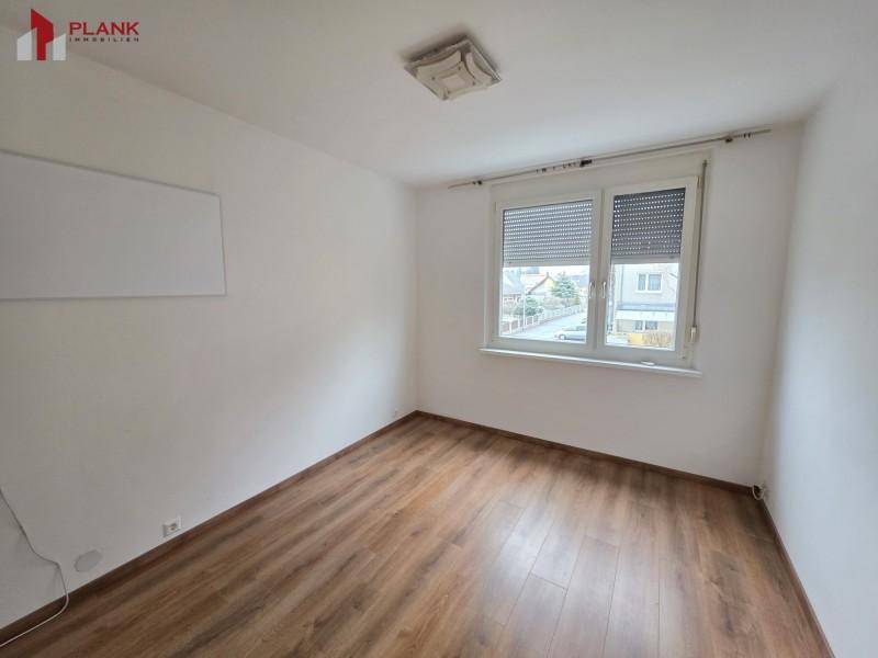 Helles Schlafzimmer mit Holzboden und Fenster mit Rollläden, bietet eine ruhige Atmosphäre.