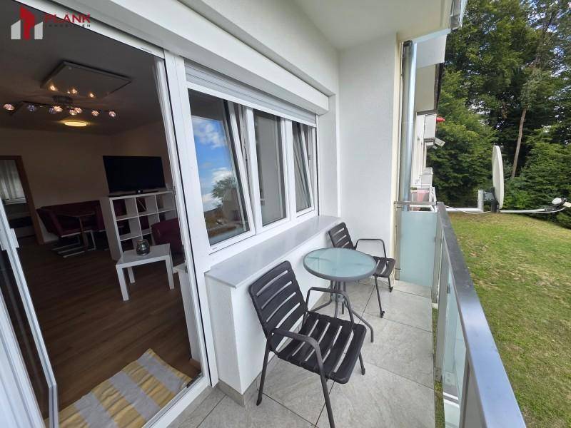Möblierter Balkon mit Tisch und Stühlen, bietet einen Blick in das Wohnzimmer.