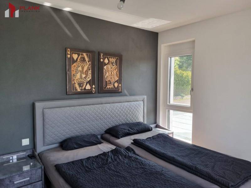 Schlafzimmer mit zwei Einzelbetten, dunkler Akzentwand und Fensterblick.