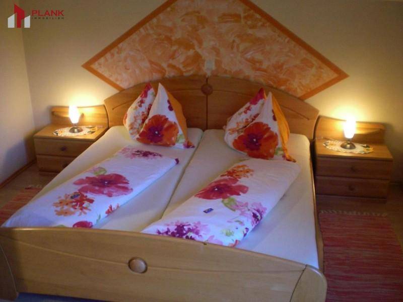 Gemütliches Schlafzimmer mit Doppelbett, Holzmöbeln und floral gemusterten Bettbezügen.