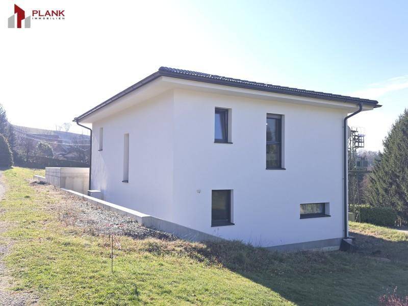 Modernes Einfamilienhaus mit weißer Fassade und schlichtem Design in ländlicher Umgebung.
