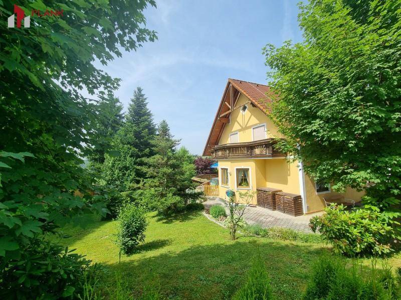 Weitläufiger grüner Garten mit altem Baumbestand und Blick auf das traditionelle Haus.