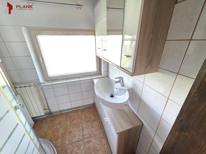 Badezimmer mit Waschbecken, Spiegelschrank und Fliesen an Wänden und Boden.
