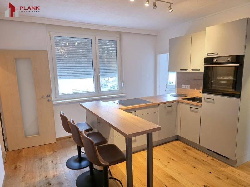 Moderne L-förmige Küche mit integrierten Geräten, Holzarbeitsplatte und Bartheke.