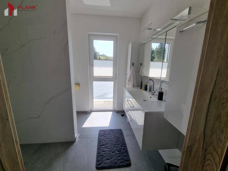 Modernes Badezimmer mit großem Waschtisch, Spiegelschrank und Fenster.