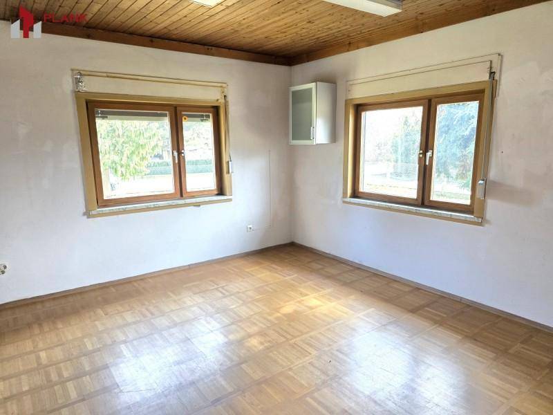 Geräumiges Zimmer mit Holzdeckenverkleidung und Parkettboden, ideal als Schlaf- oder Arbeitszimmer.