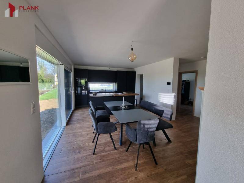 Offener Wohn- und Essbereich mit großem Esstisch, Holzboden und viel Tageslicht.