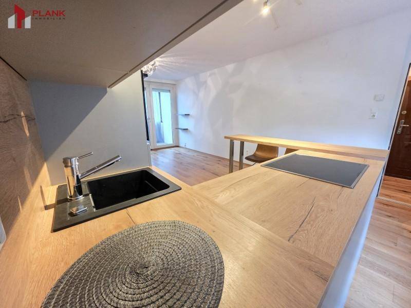 Detailansicht der modernen Küche mit Spüle, Induktionskochfeld und Holzarbeitsplatte.