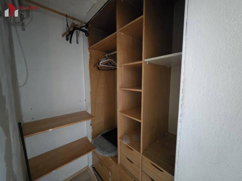 Praktischer begehbarer Kleiderschrank mit Holzregalen und ausreichend Stauraum.