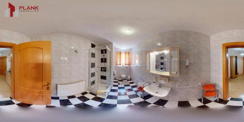 Badezimmer mit Dusche, Waschbecken und Fliesen in hellen Farben, gut beleuchtet.