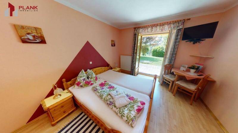 Helles Schlafzimmer mit Einzelbetten, Holzboden und direktem Zugang zum Garten.