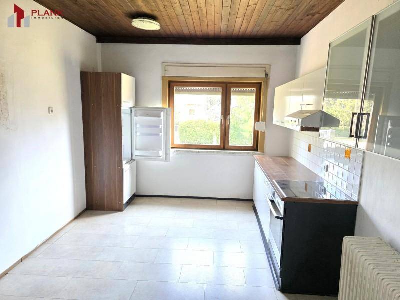 Einfache Küche mit weißen Oberschränken und integriertem Kühlschrank, ideal für eine Renovierung.