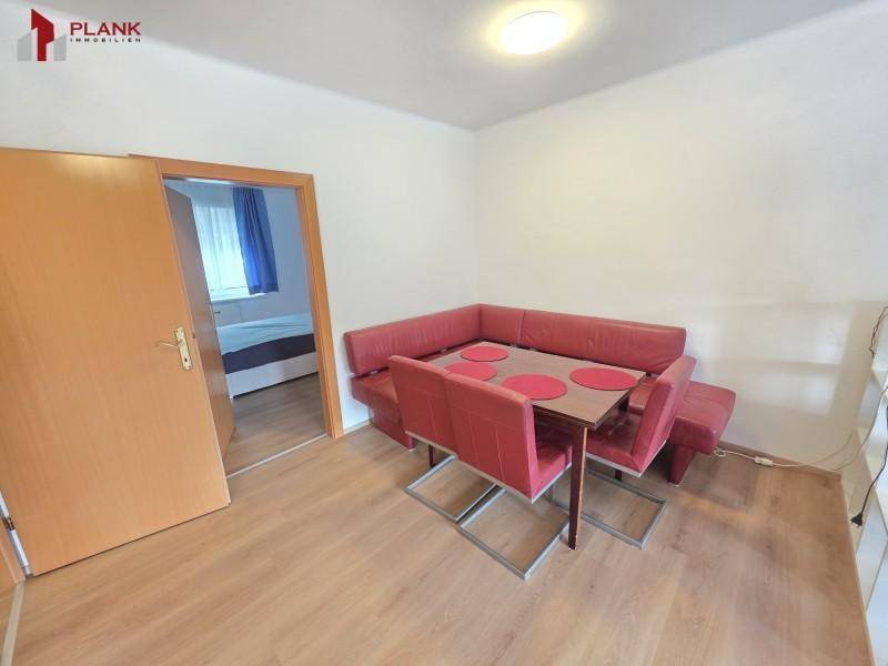 Gemütlicher Essbereich mit Eckbank und Holztisch, angrenzend an ein Schlafzimmer.