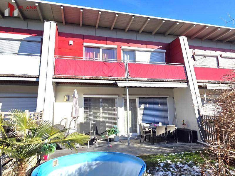 Rückseite des Reihenhauses mit möblierter Terrasse, Garten und Pool.
