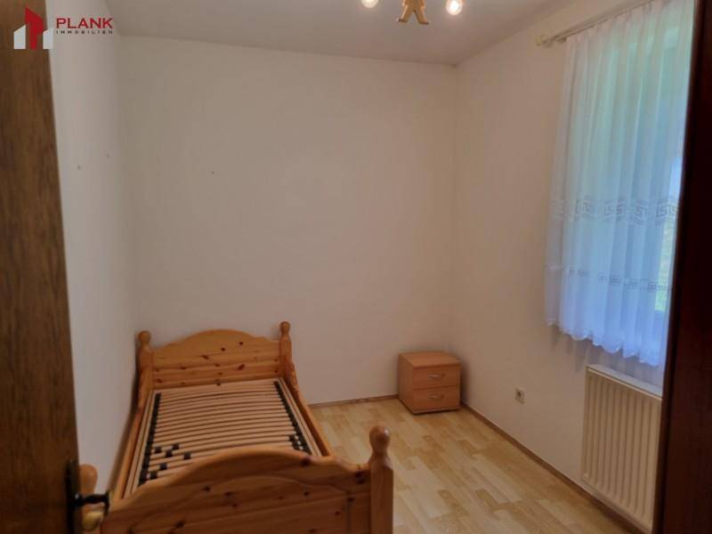 Helles Schlafzimmer mit Einzelbett aus Holz und Parkettboden.