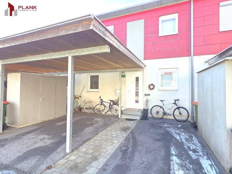 Vorderansicht des Reihenhauses mit Carport und gepflasterter Einfahrt.
