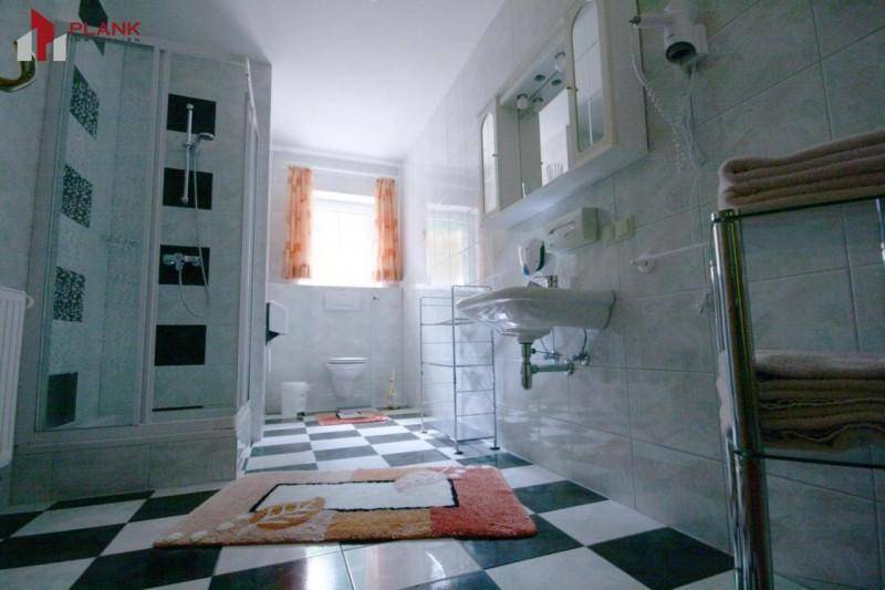 Badezimmer mit Dusche, Waschbecken und markantem schwarz-weiß kariertem Fliesenboden.