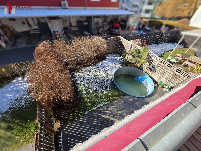 Garten mit Rasenfläche, Büschen und einem kleinen Aufstellpool im Winter.