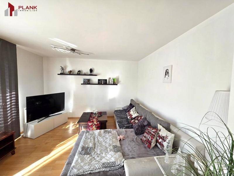 Lichtdurchflutetes Wohnzimmer mit Parkettboden, großem Sofa und moderner Einrichtung.