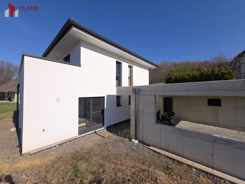 Seitenansicht eines modernen Einfamilienhauses mit weißer Fassade und großen Fenstern.