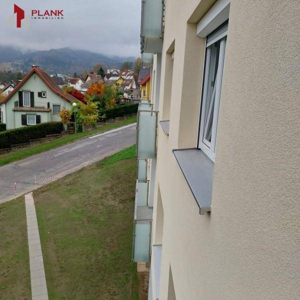Seitenansicht des Gebäudes mit Blick auf die umliegende Wohnsiedlung und grüne Hügel.
