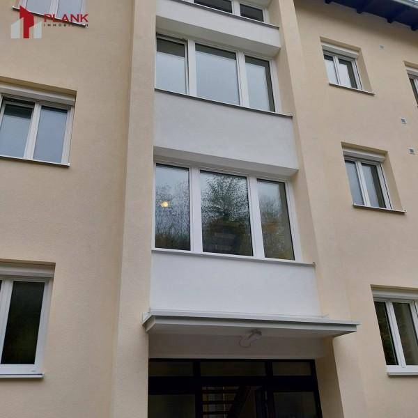 Fassade eines Mehrfamilienhauses mit mehreren Fenstern und einem Eingangsbereich.