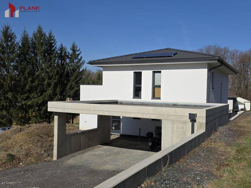 Modernes Einfamilienhaus mit integriertem Carport und Photovoltaikanlage auf dem Dach.