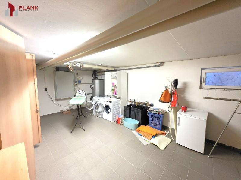 Funktionaler Hauswirtschaftsraum im Keller mit Waschmaschine, Trockner und Stauraum.