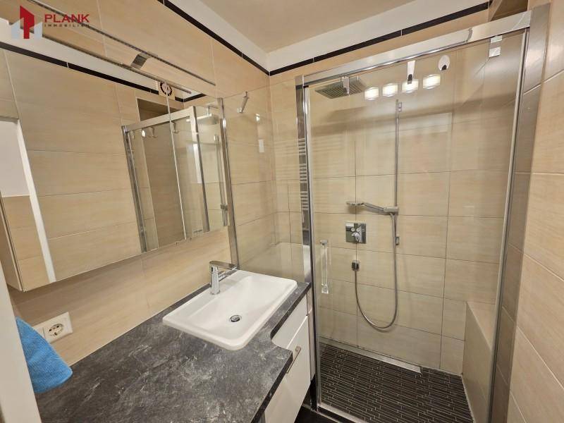 Modernes Badezimmer mit begehbarer Dusche, Einzelwaschbecken und beigefarbenen Fliesen.