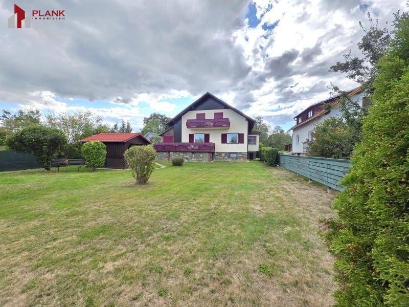 Großer Garten hinter dem Haus mit Rasenfläche, Gartenhaus und Blick auf das Gebäude.