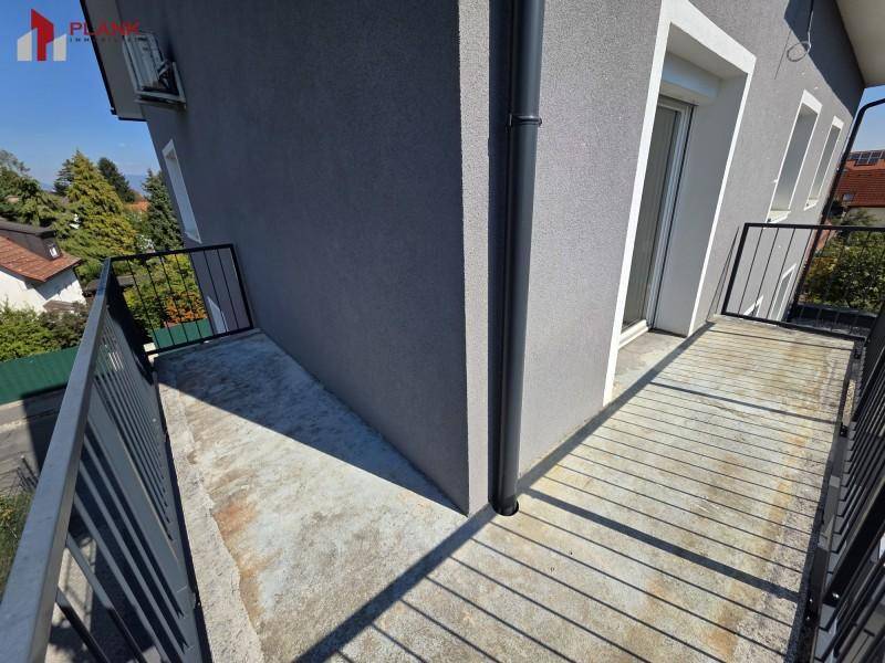 Langer Balkon mit Betonboden und schwarzem Metallgeländer entlang der Gebäudefassade.