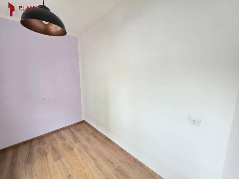 Kleiner Raum mit Holzboden und einer farbigen Akzentwand, vielseitig nutzbar.