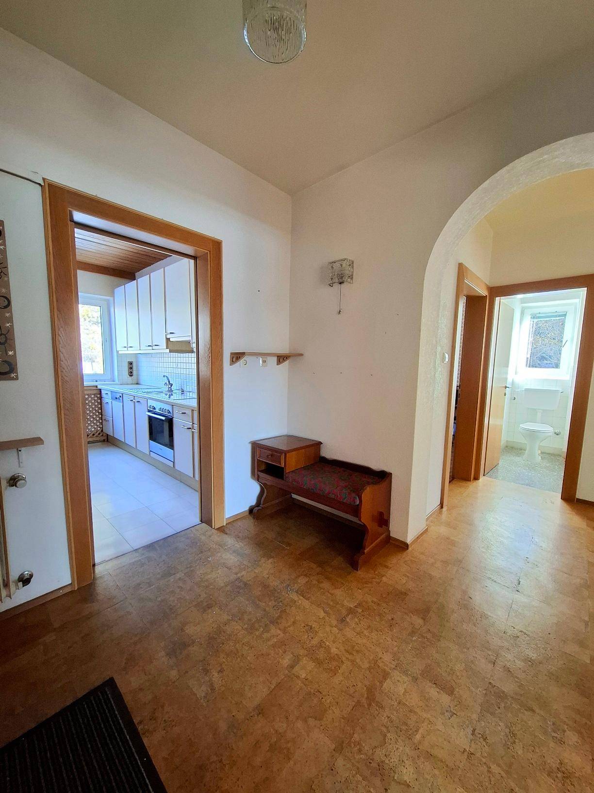 Flur mit Zugang zur Küche und einem Badezimmer, ausgestattet mit Laminatboden.
