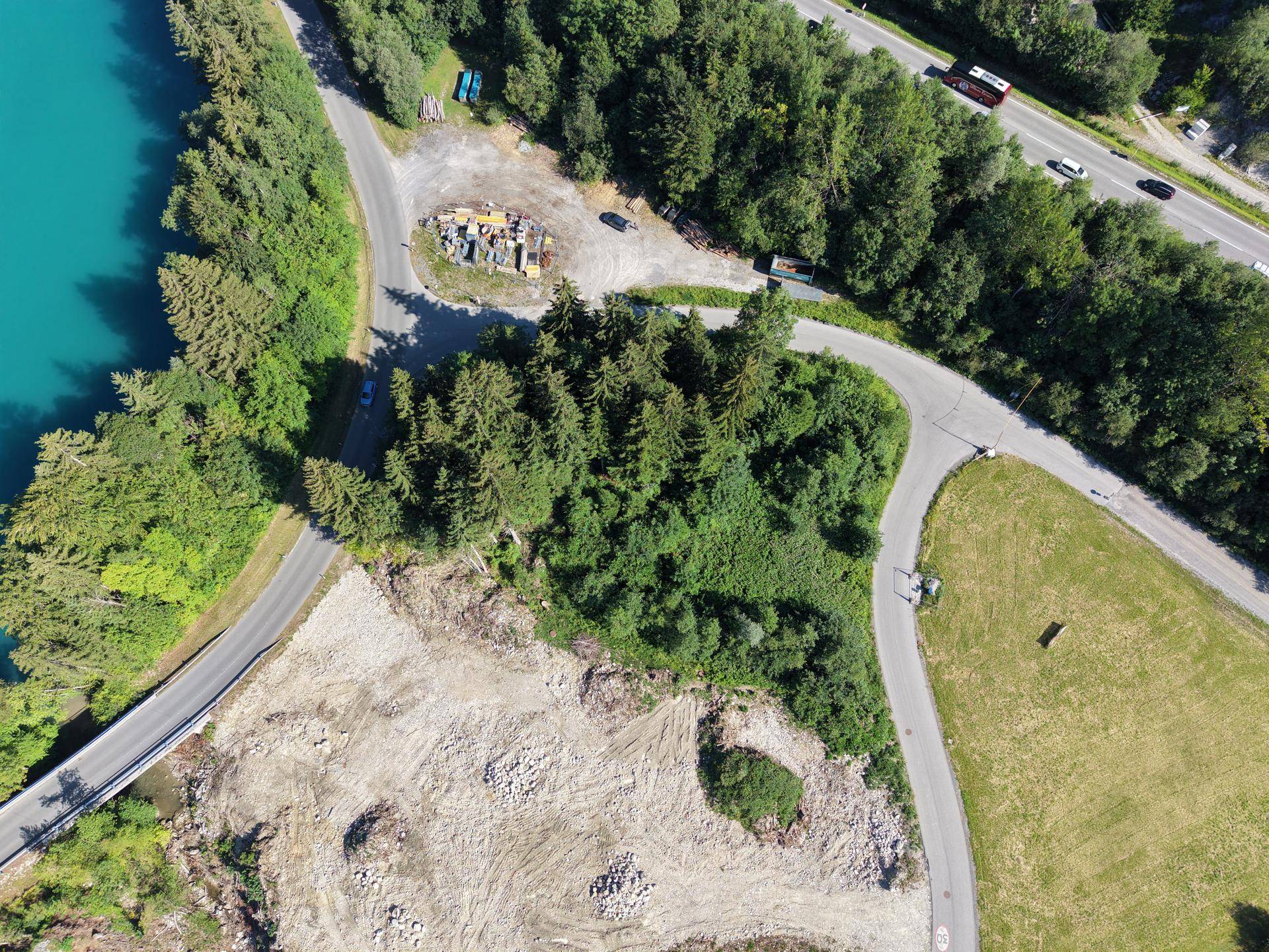 Luftaufnahme eines Grundstücks mit angrenzendem Fluss, Wald und einer Autobahn im Hintergrund, umgeben von Natur.