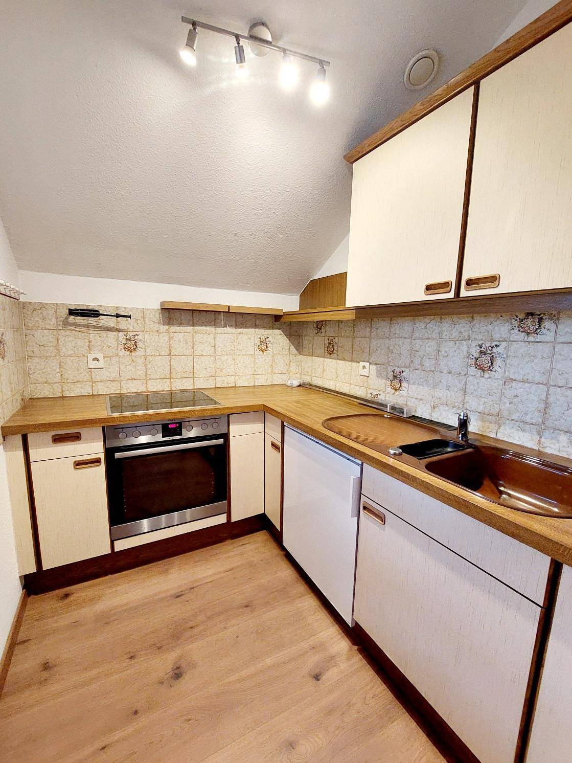 Kleine Küche im Dachgeschoss mit Holztheke, Einbaugeräten und traditionellen Fliesen.