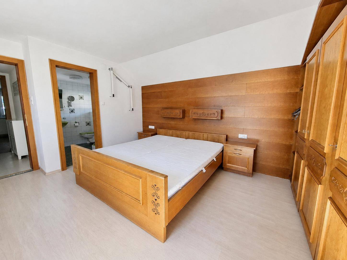 Schlafzimmer mit traditionellem Holzbett, Einbauschränken und direktem Zugang zum Bad.