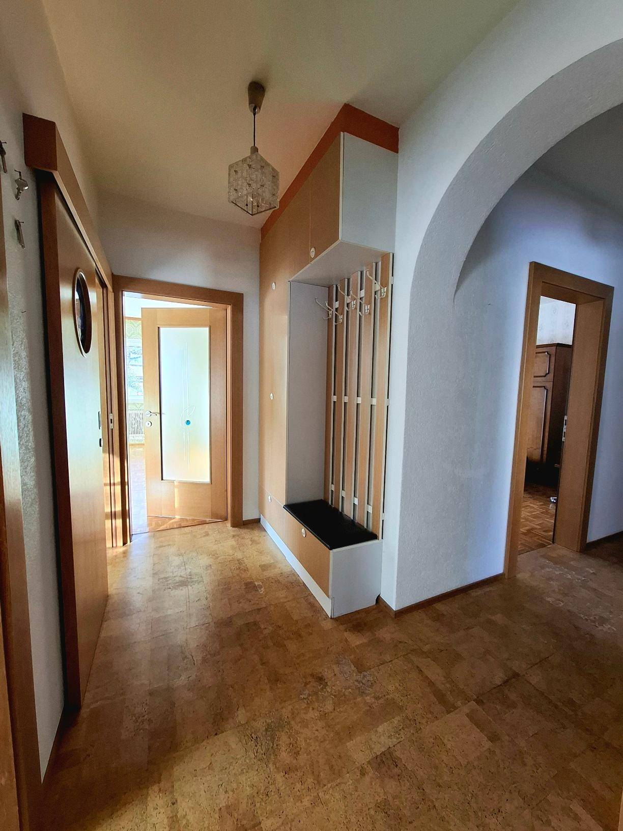 Heller Flur mit Garderobe, Laminatboden und einem dekorativen Torbogen.