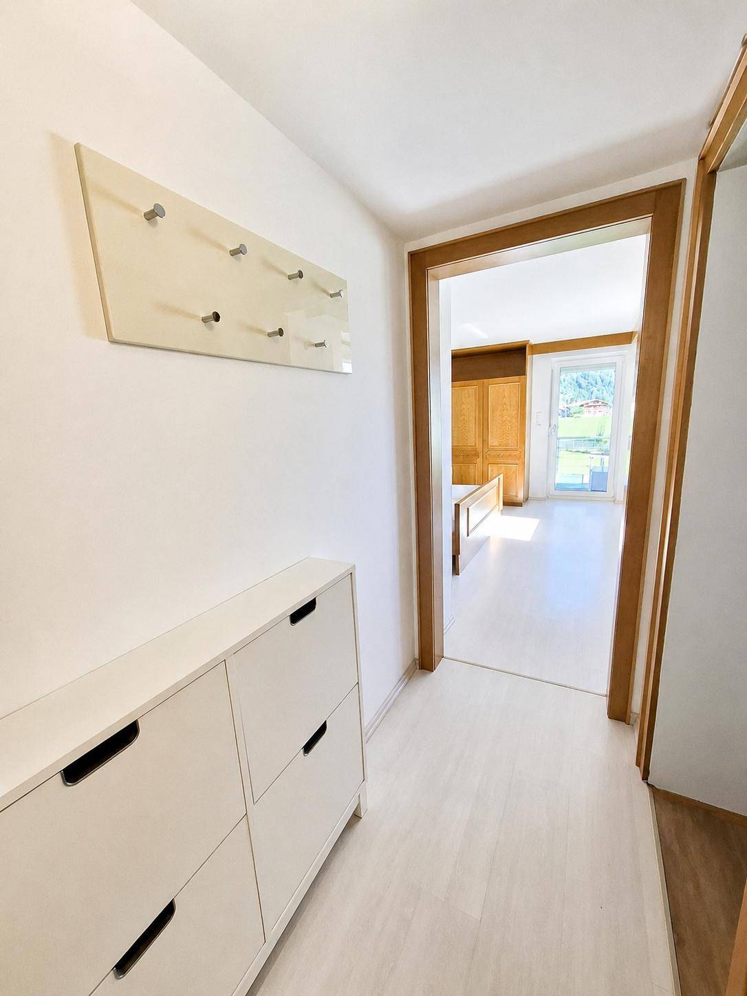 Eingangsbereich mit Schuhschrank und Garderobe, führt zu einem Schlafzimmer.