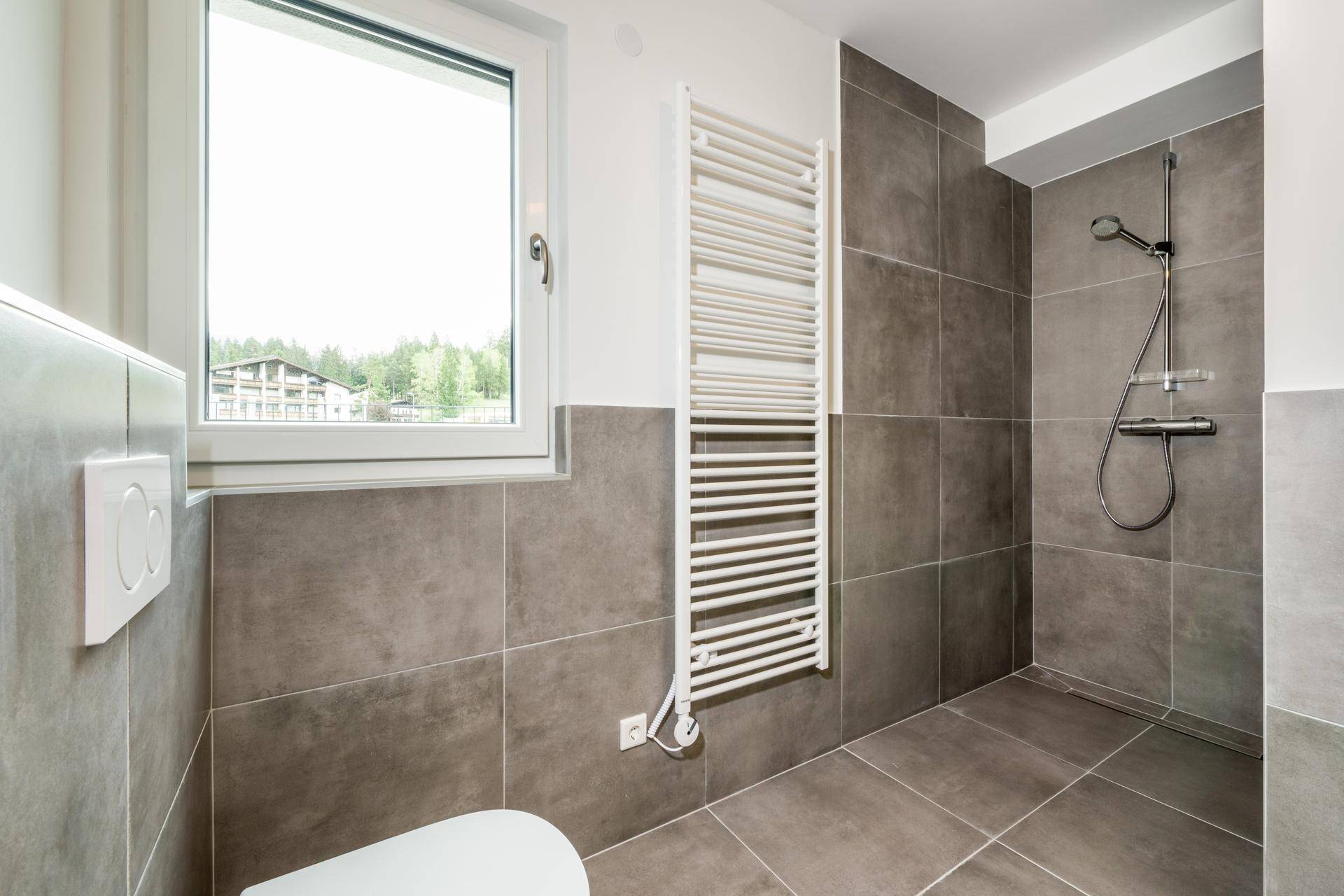 Zeitgemäßes Badezimmer mit ebenerdiger Dusche, grauen Fliesen und Fenster.