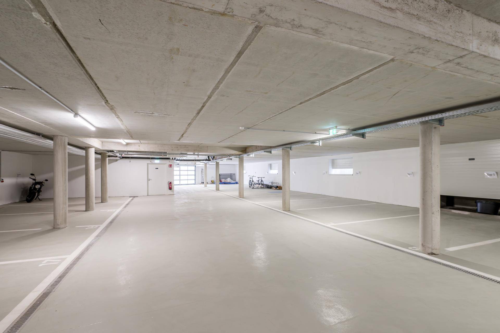Geräumige Tiefgarage mit Betonboden und markierten Stellplätzen für Fahrzeuge.