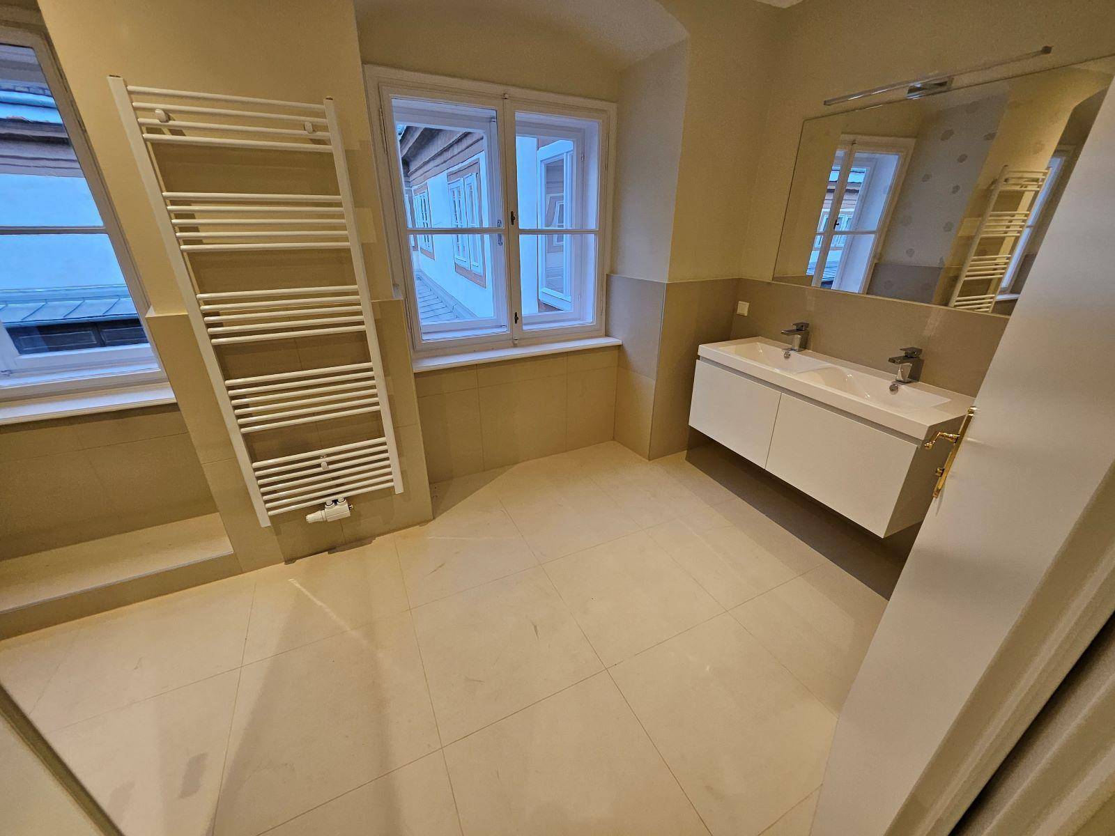Modernes Badezimmer mit Doppelwaschbecken, beheiztem Handtuchhalter und Fenster.