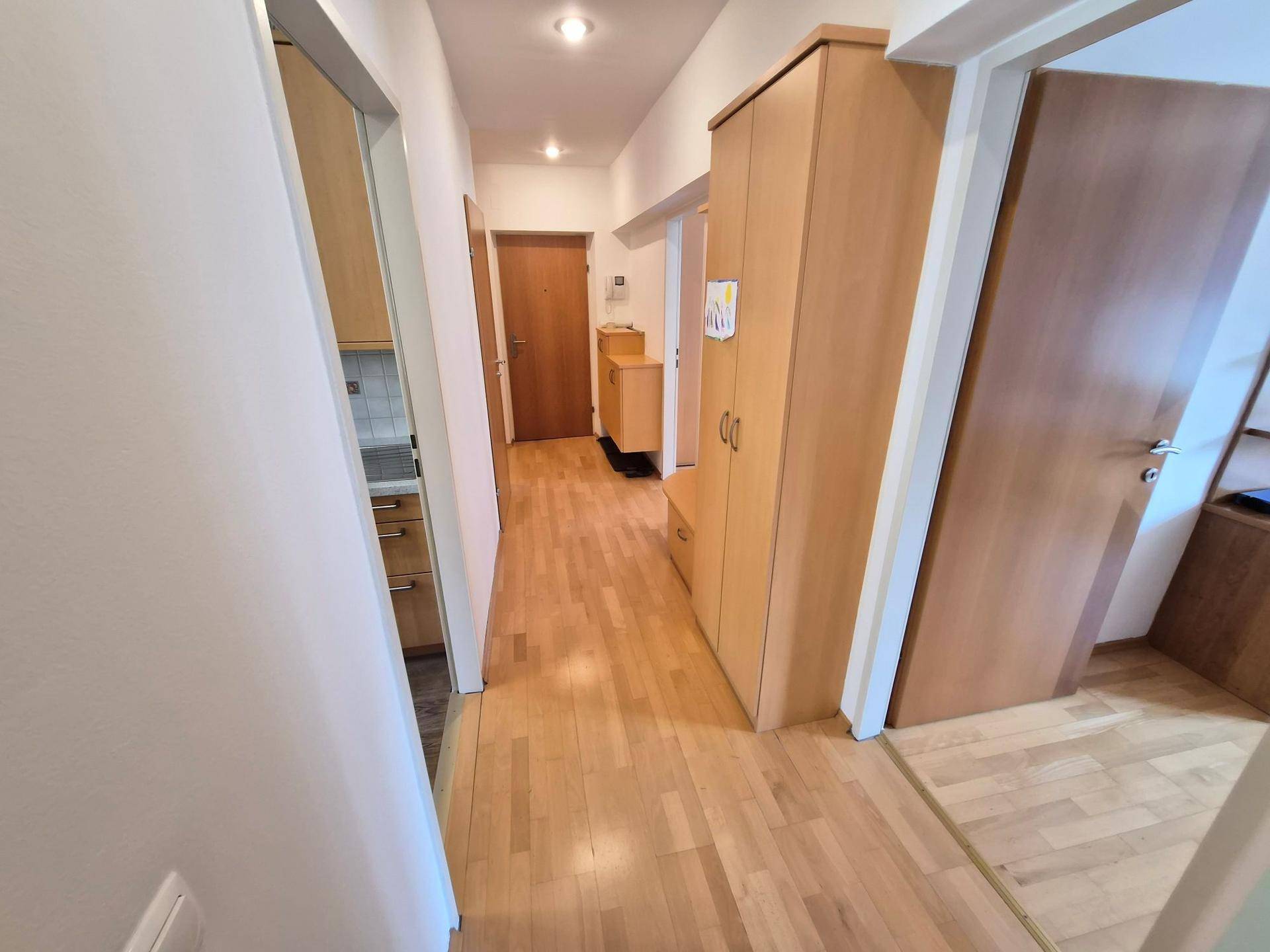 Langer Flur mit Holzfußboden und praktischen Einbauschränken, der verschiedene Räume verbindet.